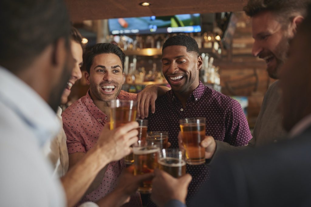 Group Of Male Friends On Night Out Drinking Beer In Bar Together