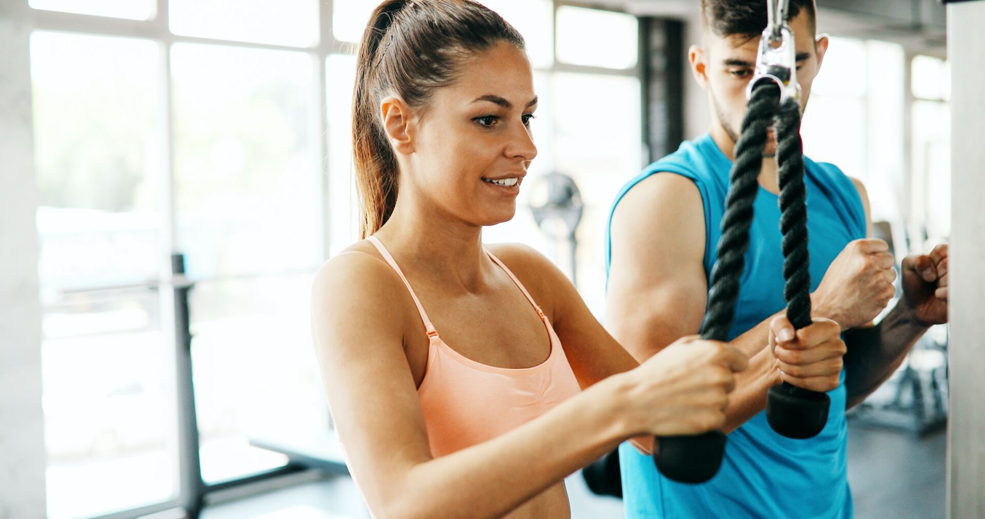 Personal trainer helping fit woman in gym