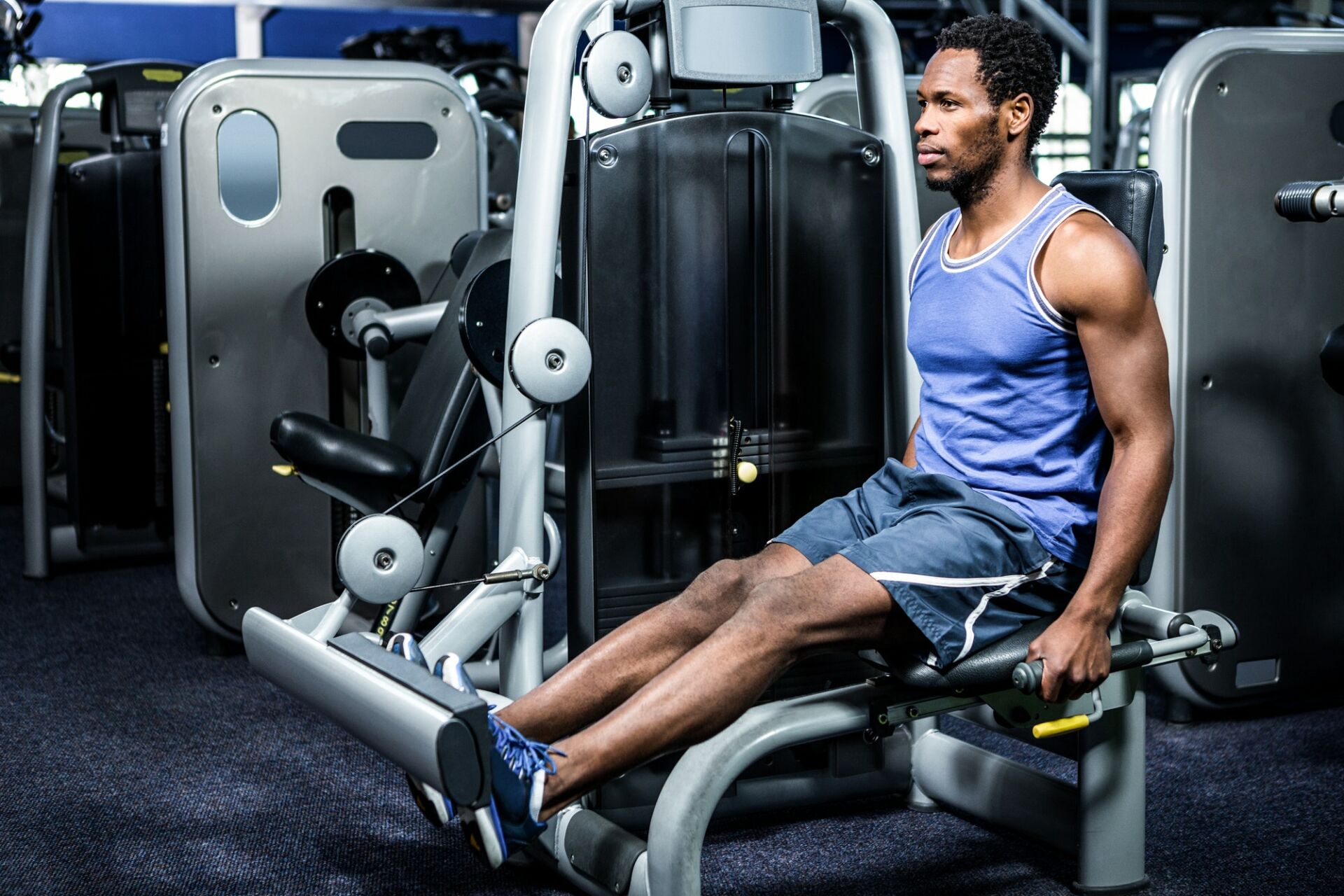 Serious muscular man using exercise machine at gym