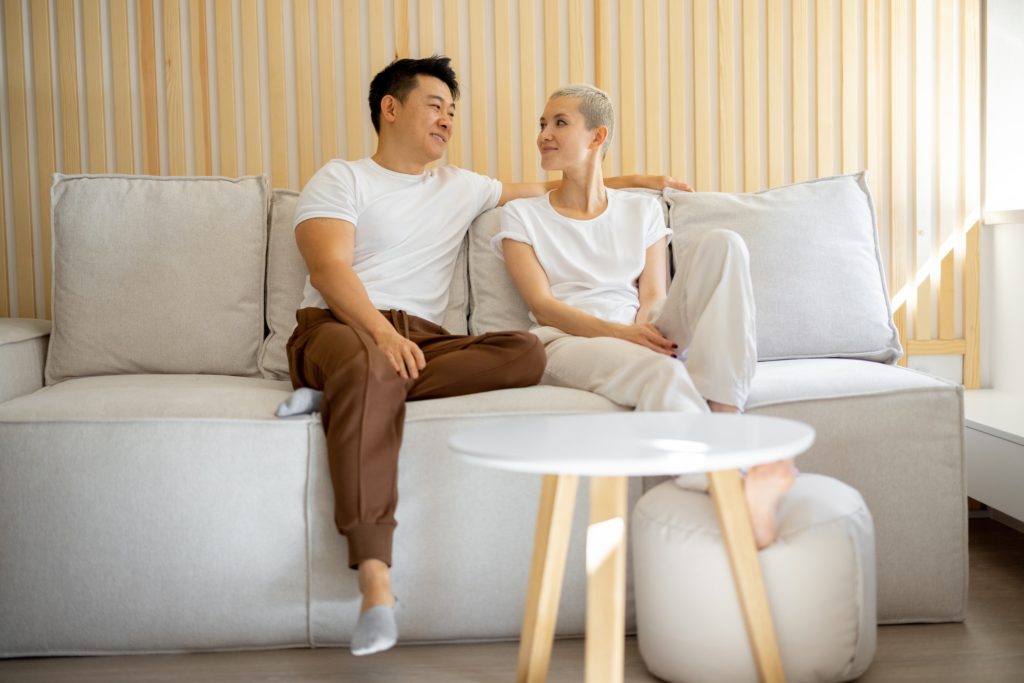 Multiracial couple sit and rest on sofa at home