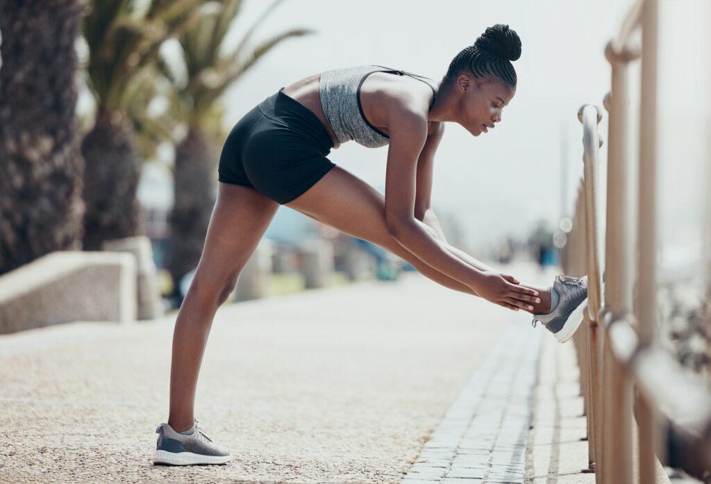 Fitness, running and black woman stretching legs outdoors to start marathon training, cardio exercise, Sustainable Fitness Routine
